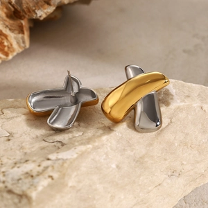 Macro shot of 18k gold and silver cross earrings on a natural textured rock background