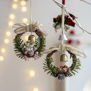 Weihnachtskranz mit Kiefernnadeln, roten Schleifen und Glocken auf warmem Bokeh-Hintergrund