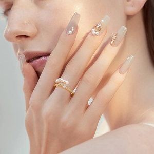 Layered gold beaded and white pearl ring set with crystal accent on model's hand