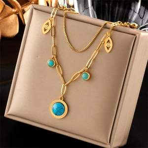 Detail of gold double-layer necklace featuring turquoise beads and evil eye pendant charms