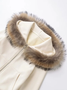 Close-up of fluffy faux fur collar and smooth metal zipper on off-white hoodie