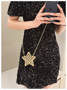 Detail of star-shaped golden metallic crossbody bag with delicate bead chain and mesh texture