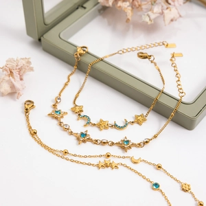 Detail of 18K gold stainless steel bracelets with moon and star charms in a gift box