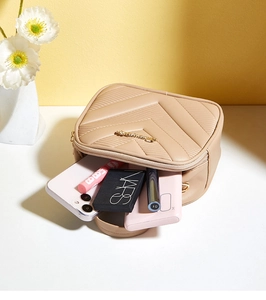 Detail view of beige quilted crossbody bag showing storage capacity for cosmetics and phone