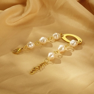 Detailed view of golden bracelet with baroque pearls on champagne silk background