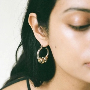 Detail of 18K gold and silver stainless steel multi-hoop earrings worn by a model