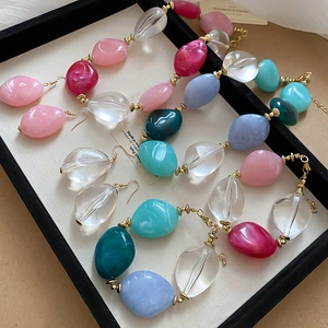 Close-up of colorful acrylic oval beaded necklace and earring set with spring theme prop