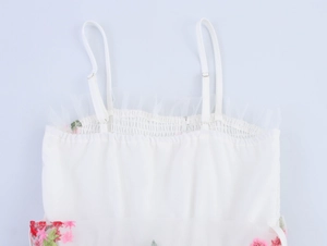 Détail d'une robe en tulle blanc avec broderie florale et bustier élastique à smocks