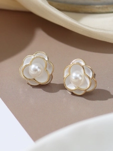 Close-up of white camellia stud earrings with pearl center and gold metal details
