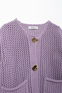 Détails de la maille épaisse violette et des boutons métalliques du cardigan