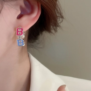 Detail of pink and blue enamel letter B earrings with zircon stone on model
