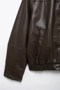 Detalle de chaqueta de piel sintética marrón oscuro con bolsillos y dobladillo elástico