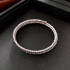 Polished silver twisted rope multi-layer cuff bracelet on a dark textured background