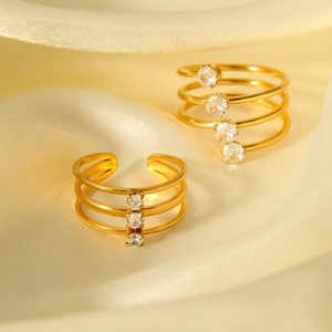Nahaufnahme von dreilagigem goldfarbenem Edelstahlring mit Zirkonia auf Seidenstoff
