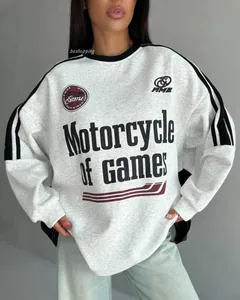 Detail of light grey oversized sweatshirt featuring athletic side stripes and graphic print