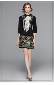 Detail of colorful floral embroidery and bow neckline on a black slim dress