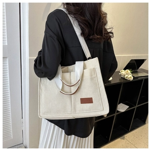 Model wearing large off-white corduroy tote bag with brown leather FASHION label
