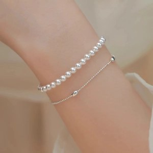 Elegante bracciale a doppio strato con perle bianche e sfere d'argento sul polso