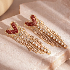 Detailed macro view of long gold tassels and red heart crystals on premium earrings