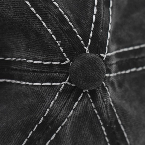 Macro shot of baseball cap top featuring washed fabric, contrast stitching, and central button
