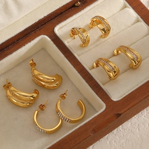 Set of four pairs of 18k gold plated C-shaped earrings with zircon accents on a wooden box