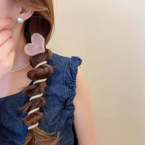 Détail de la pince à cheveux cœur rose et des élastiques spirales pour tresses bulles