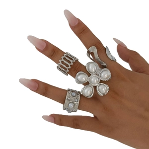Five-piece silver stainless steel ring set with floral and pearl accents on model's hand