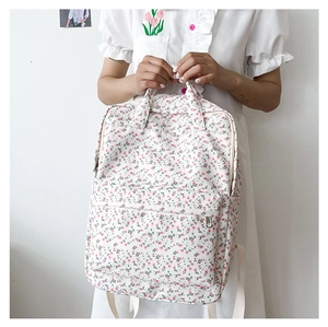 Detailed back view of pink floral canvas backpack worn by a model in casual style