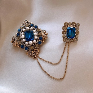 Vintage gold plated double brooch with blue crystals and pearls on silk background