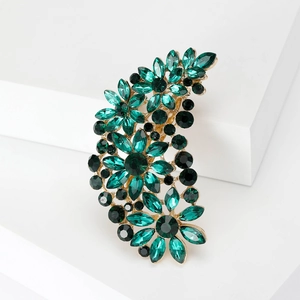 Detailed close-up of a floral brooch featuring green crystals on a gold-plated base