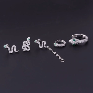 Silver snake earring set with green and white cubic zirconia on a dark background