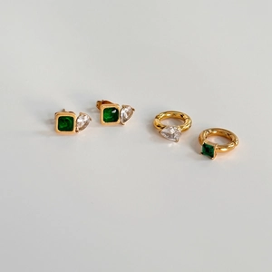 Detailed macro view of gold-plated square emerald and pear-shaped zircon earring set