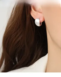 Detail of silver hoop earrings with a matte brushed finish on a female model's ear