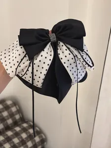 Detail of French chiffon bow hair claw with black polka dots and rhinestone center