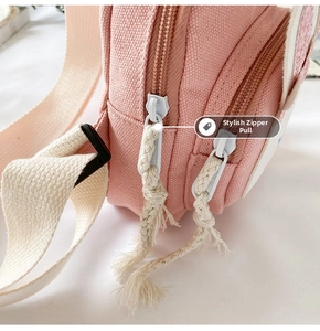 Detail of pink canvas bag featuring dual zippers with cream woven rope pullers