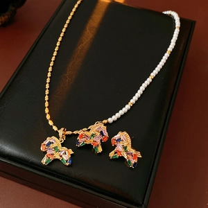 Detail of vintage necklace with gold bead chain, pearls and three colorful dog pendants
