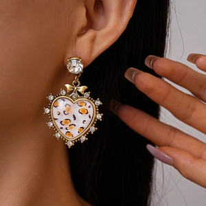 Close-up of leopard heart earring with sparkling rhinestones and a gold bow detail