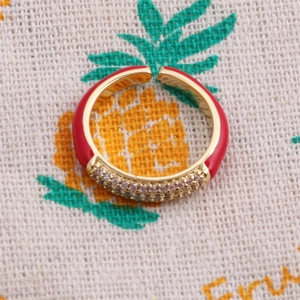 Detailed close-up of golden adjustable ring with red enamel and pavé zircon stones