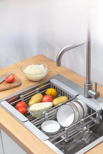 Macro shot of an adjustable stainless steel sink rack holding fresh vegetables and dishes