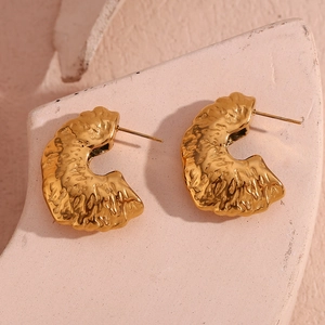 Macro view of gold plated stainless steel fan earrings with hammered metal texture