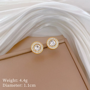 Detail of 1.1cm gold halo stud earrings with cubic zirconia on white silk