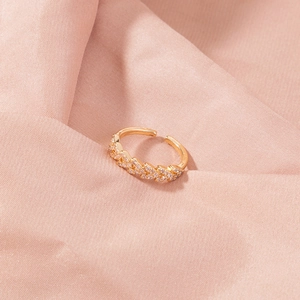 Close-up of gold-plated leaf ring with pavé zircons on soft pink textured fabric