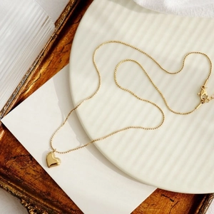 Detail shot of a minimalist gold heart pendant necklace on a decorative tray