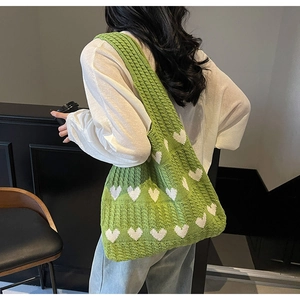 Detalle de bolso de punto verde con patrones de corazones blancos al hombro