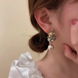 Close-up of floral snowflake earring with colorful zircons and hanging pearl on model