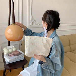 Detail of floral daisy embroidered cotton pouch held by hand in a cozy lifestyle setting
