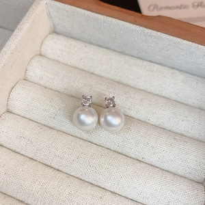 Vue macro de boucles d'oreilles en perles avec zircons dans un écrin à bijoux beige