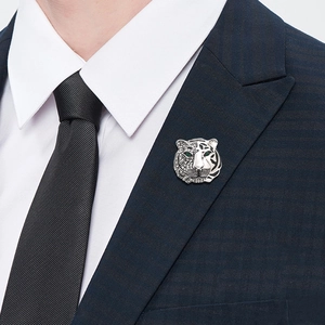 Silver tiger brooch with crystals and green gemstone eyes on a blue suit lapel