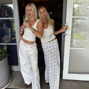 Femmes chics en jupe dentelle et pantalon cargo posant avec verres sous le soleil