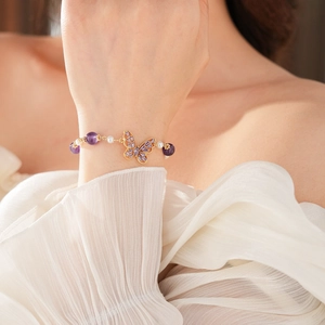Detailed shot of a gold butterfly bracelet with purple amethyst beads and white pearls